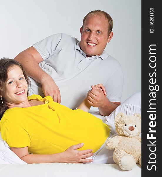 Young couple on a couch. The woman is pregnant and they seem to be in love. Young couple on a couch. The woman is pregnant and they seem to be in love.