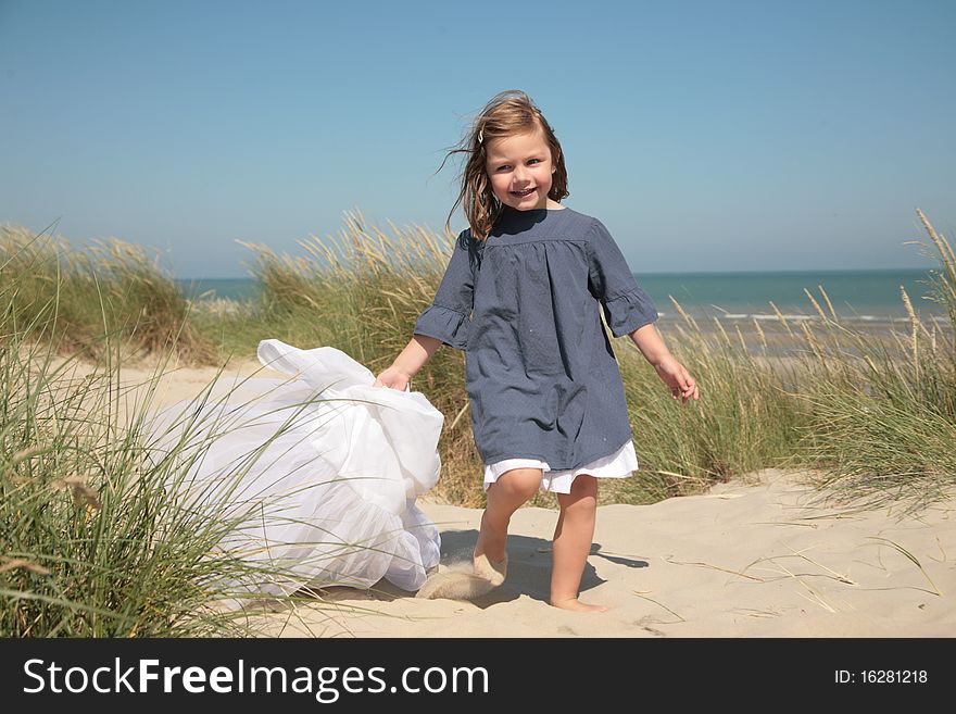 Little girl running on the sand and holding a veil. Little girl running on the sand and holding a veil