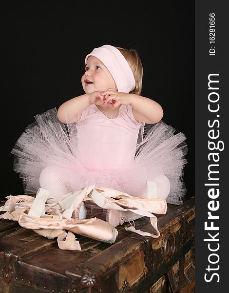 Baby ballerina sitting on an antique trunk