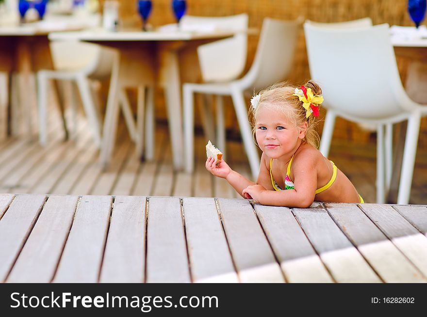 Cute little girl sits in outdoor cafe and nave a snack. Cute little girl sits in outdoor cafe and nave a snack