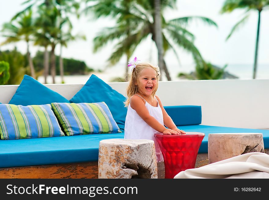 Happy toddler girl have a fun in beach cafe in exotic coastline background. Happy toddler girl have a fun in beach cafe in exotic coastline background