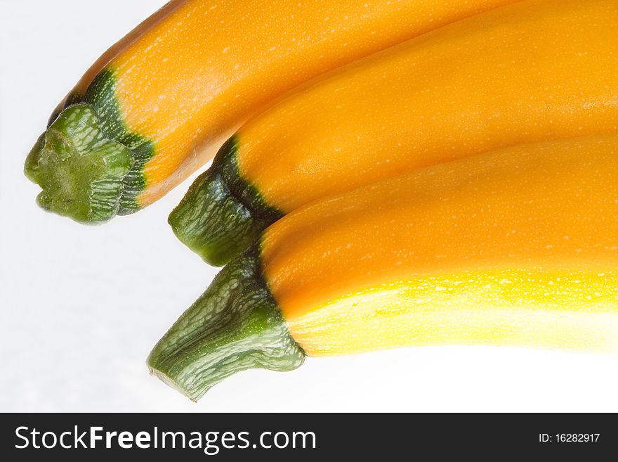 Three yellow courgettes against a white background