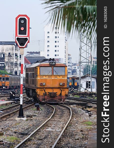 Orange Train locomotive approaching to Bangkok Railway Station Thailand with Red Train Signals