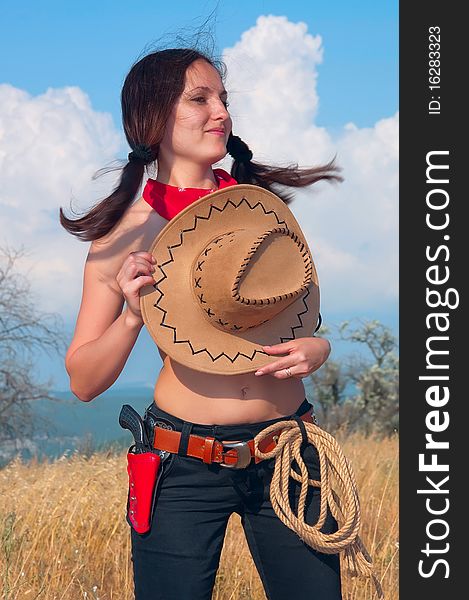 Girl cowboy in the field with  hat on  chest wind and space