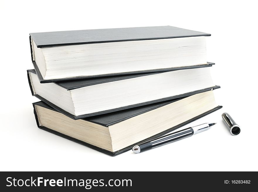 Stack of old books with black covers and a pen isolated on white. Stack of old books with black covers and a pen isolated on white