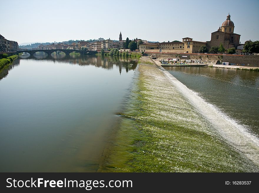 River arno flowing through florence with church in the background