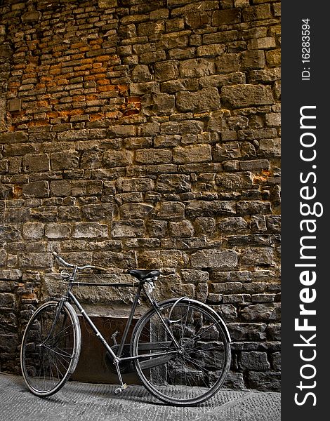 An old bike standing on a brick wall