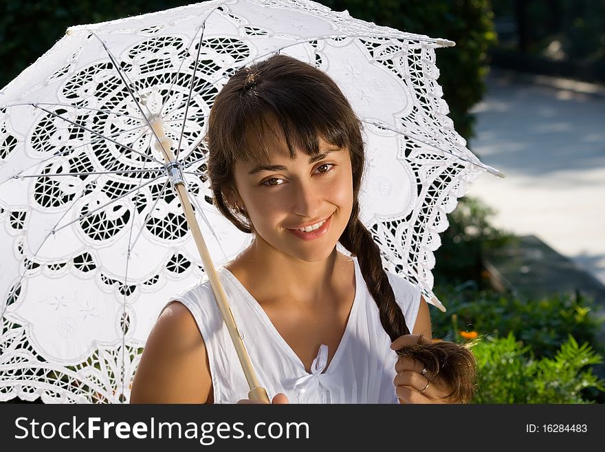 Portrait of a cheerful young lady with lacy umbrella in the park. Portrait of a cheerful young lady with lacy umbrella in the park