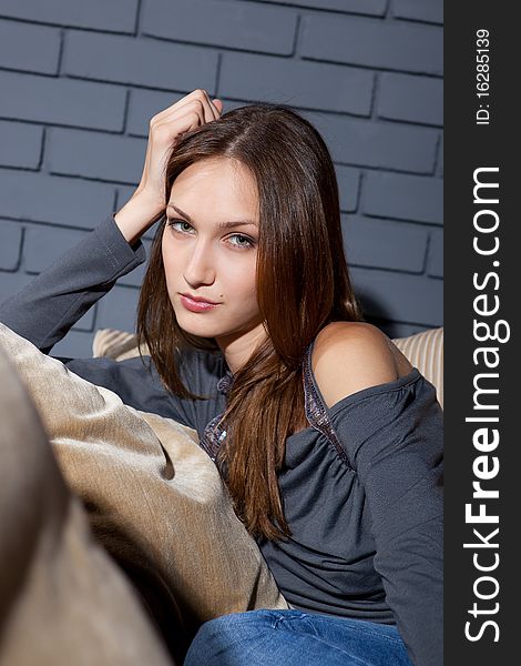 Young adult sitting on the sofa against brick background. Young adult sitting on the sofa against brick background