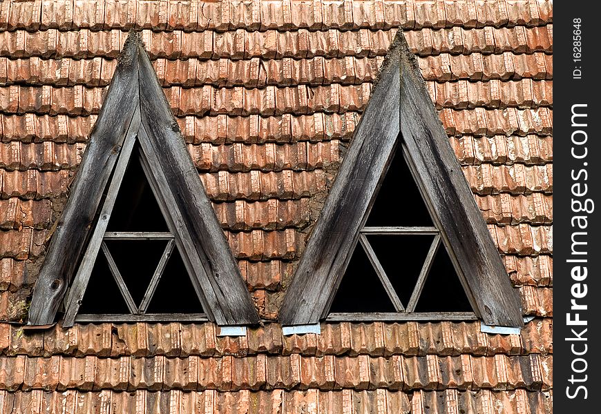 Old obsolete roof with red tile and triangular wooden window. Old obsolete roof with red tile and triangular wooden window.