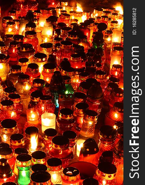 Red, yellow and green candles burning at a cemetery