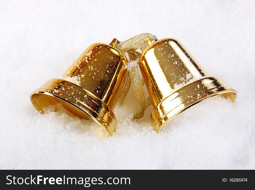 Gold christmas bells over snow - close up