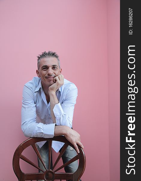 Man with blue shirt leaning on a wooden chair. Man with blue shirt leaning on a wooden chair