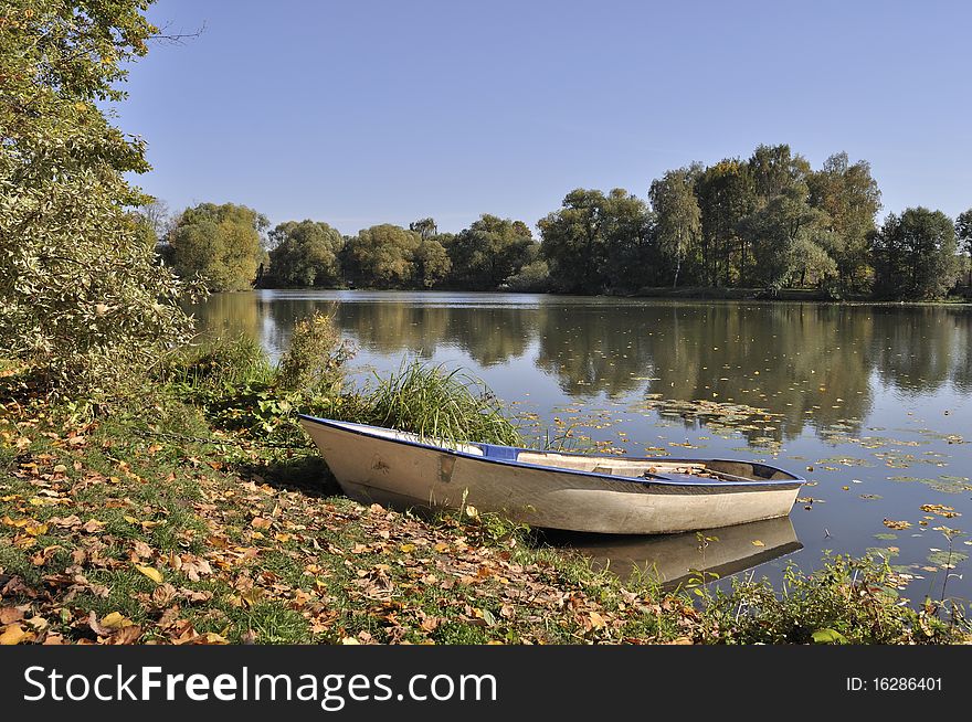 Boat on the lake bank in park, sunny autumn day. Boat on the lake bank in park, sunny autumn day