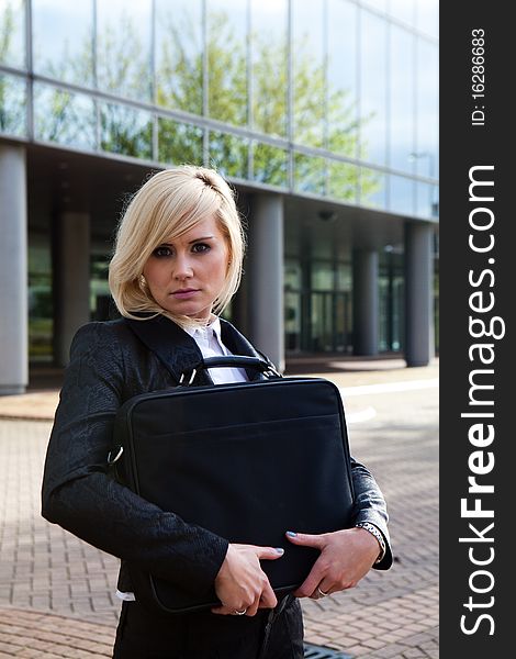 Beautiful business woman holding a bag at modern building