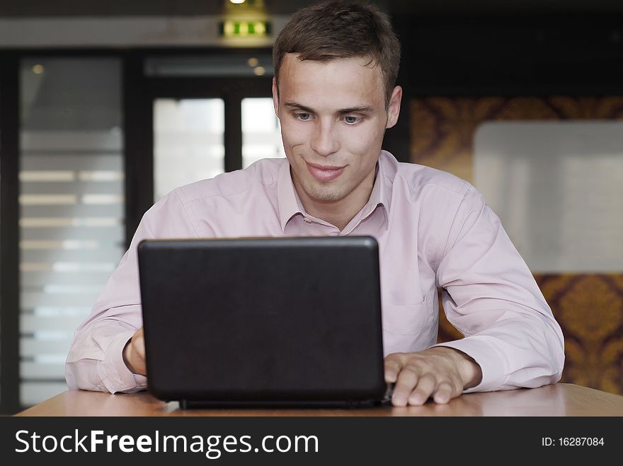 Smiling businessman  working behind the black laptop. Smiling businessman  working behind the black laptop