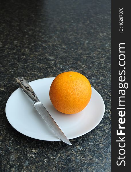 An orange fruit on a white plate with a knife. An orange fruit on a white plate with a knife