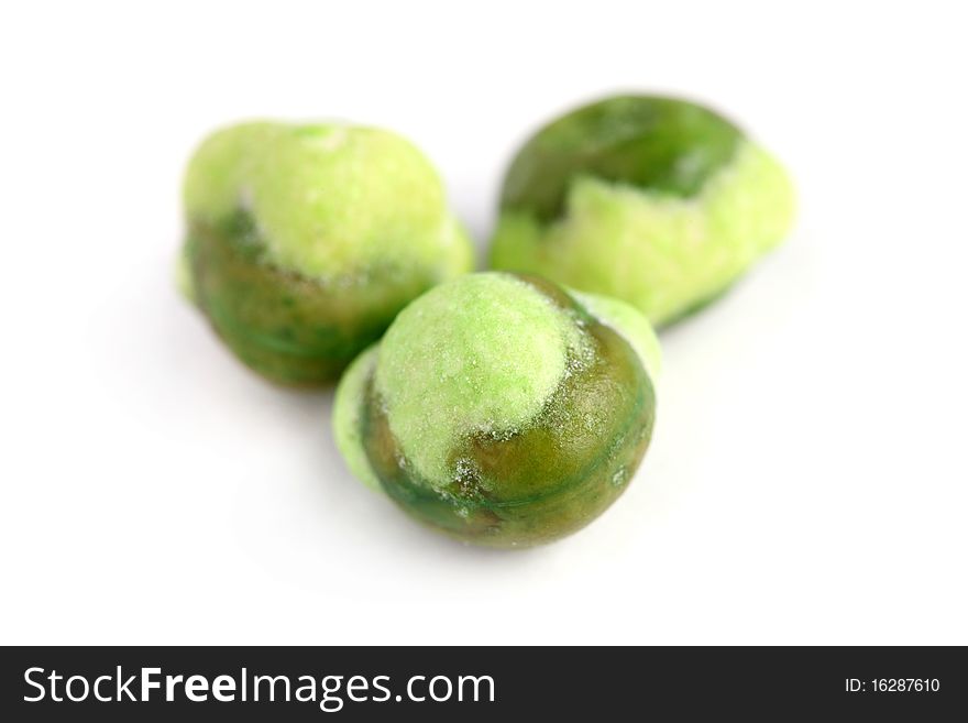 Macro shot of three wasabi coated green peas isolated on white background.