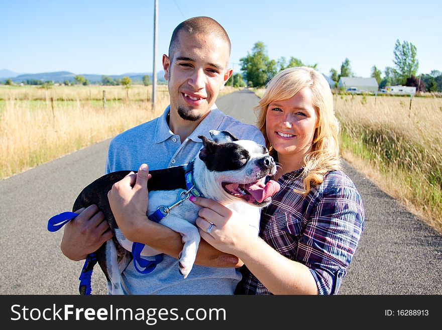 A young engaged couple and their boston terrier dog.
