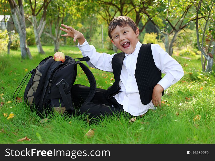 Schoolboy with backpack and apple outdoors