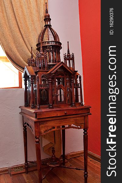 Intricate wood carved birdcage in the form of a palace on table. Intricate wood carved birdcage in the form of a palace on table