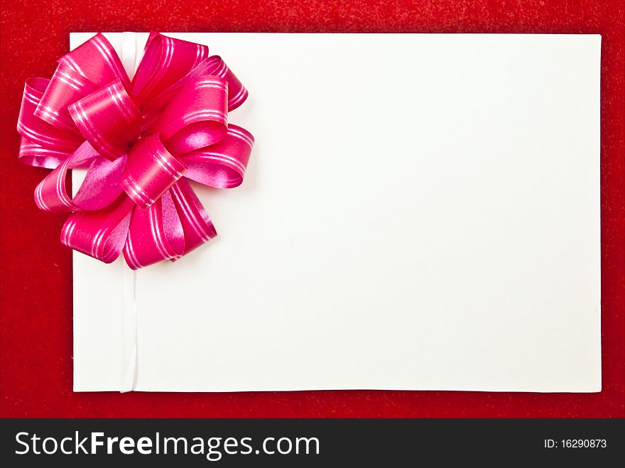 White paper blank with bow on red background. White paper blank with bow on red background