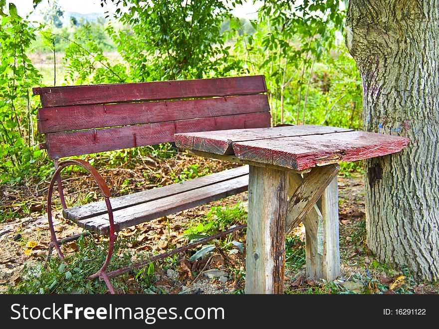 A red table with a chair near a tree