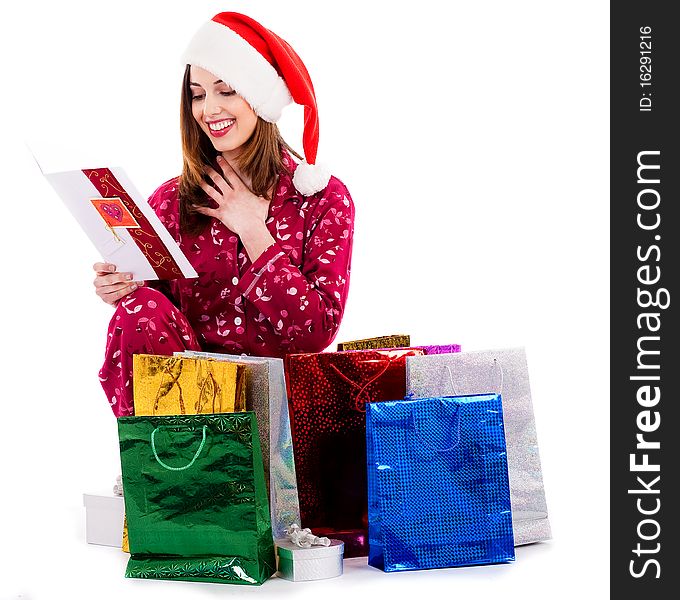 Young lady reading christmas greeting card with gift bags around her. Young lady reading christmas greeting card with gift bags around her