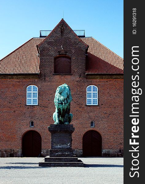 Old brick house in Copenhagen with copper statue of seated lion in front, Denmark. Old brick house in Copenhagen with copper statue of seated lion in front, Denmark