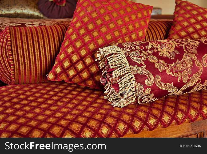 Red and gold cushions at end of bed in luxurious bedroom. Red and gold cushions at end of bed in luxurious bedroom