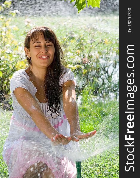 Pretty young lady having fun on the lawn amoung the sprinklers. Pretty young lady having fun on the lawn amoung the sprinklers