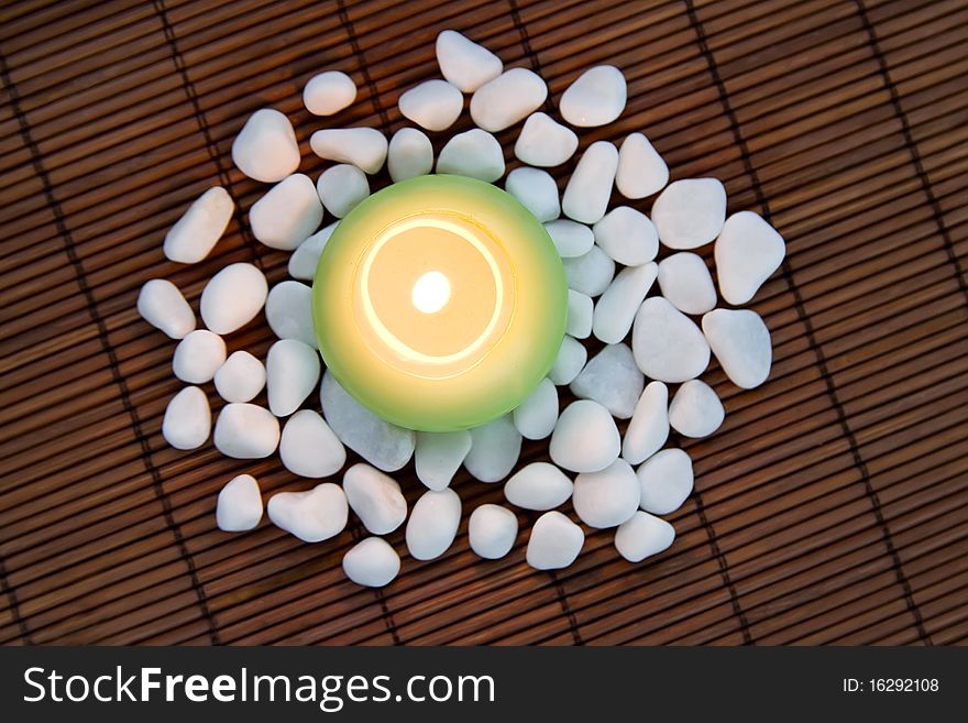 Composition with white zen stones and burning candle, symbolizing harmony, calmness and relaxation. Composition with white zen stones and burning candle, symbolizing harmony, calmness and relaxation