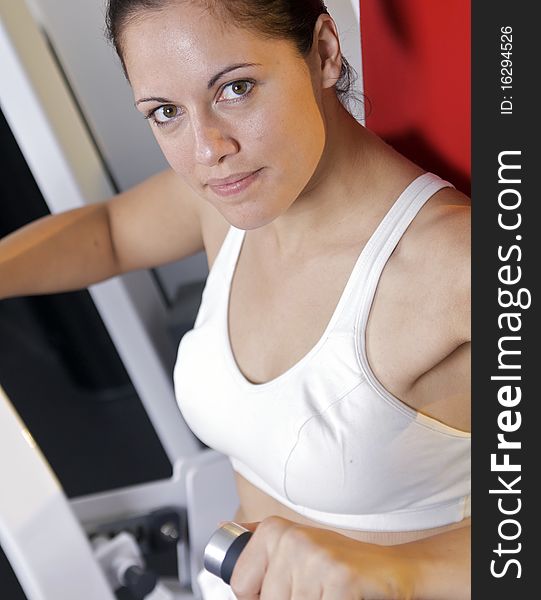 A caucasian woman uses a weight machine at the gym