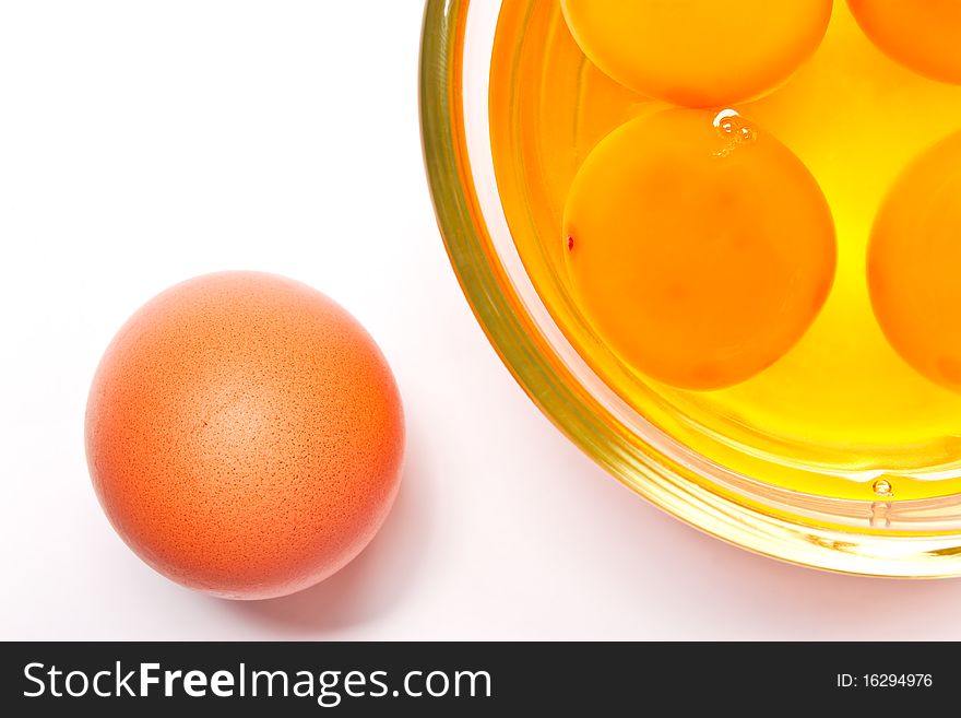 Yolks in a glass, and egg on white background.