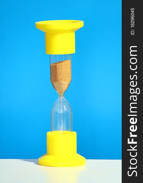 Sand hourglass on blue background