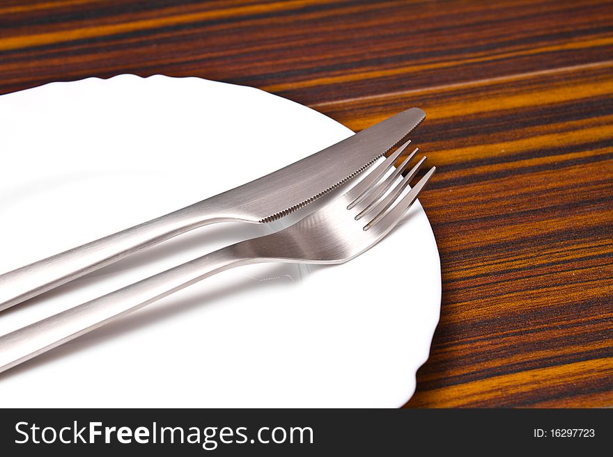 Aluminum fork and knife on a white plate. Aluminum fork and knife on a white plate