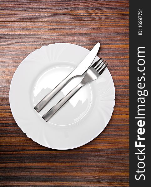 Aluminum fork and knife on a white plate. Aluminum fork and knife on a white plate