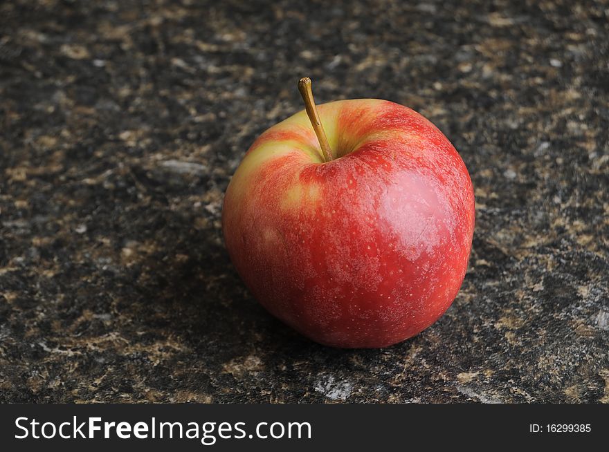 A red apple on a black kitchen countertop. A red apple on a black kitchen countertop.