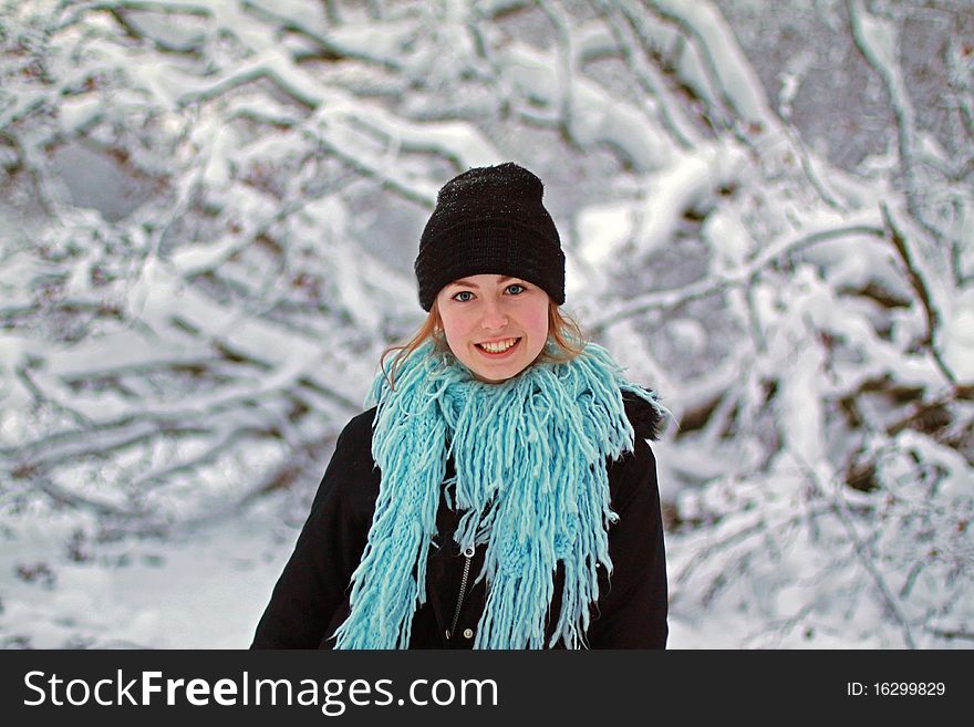 Girl in hat and scarf with snow covered tree in background. Girl in hat and scarf with snow covered tree in background