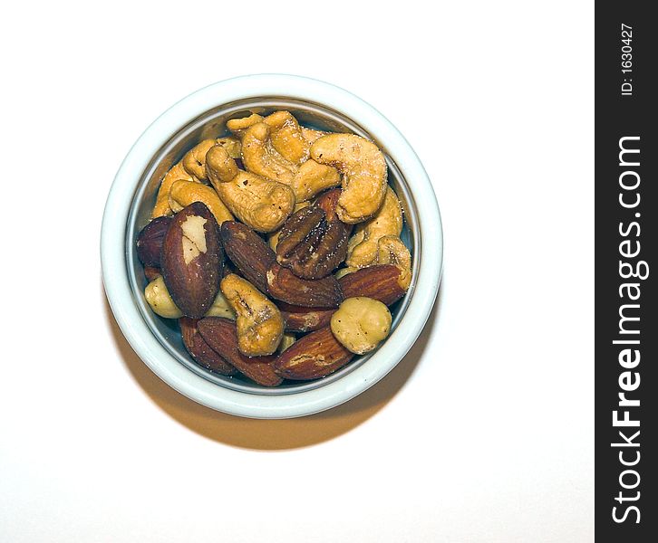 Mixed nuts in a white ceramic cup, on a white background