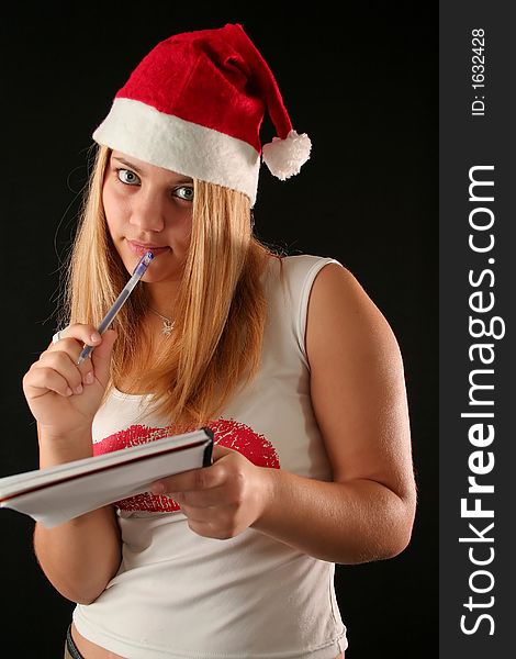 Christmas blonde girl with pencil and bloc notes thinking and writing. Christmas blonde girl with pencil and bloc notes thinking and writing
