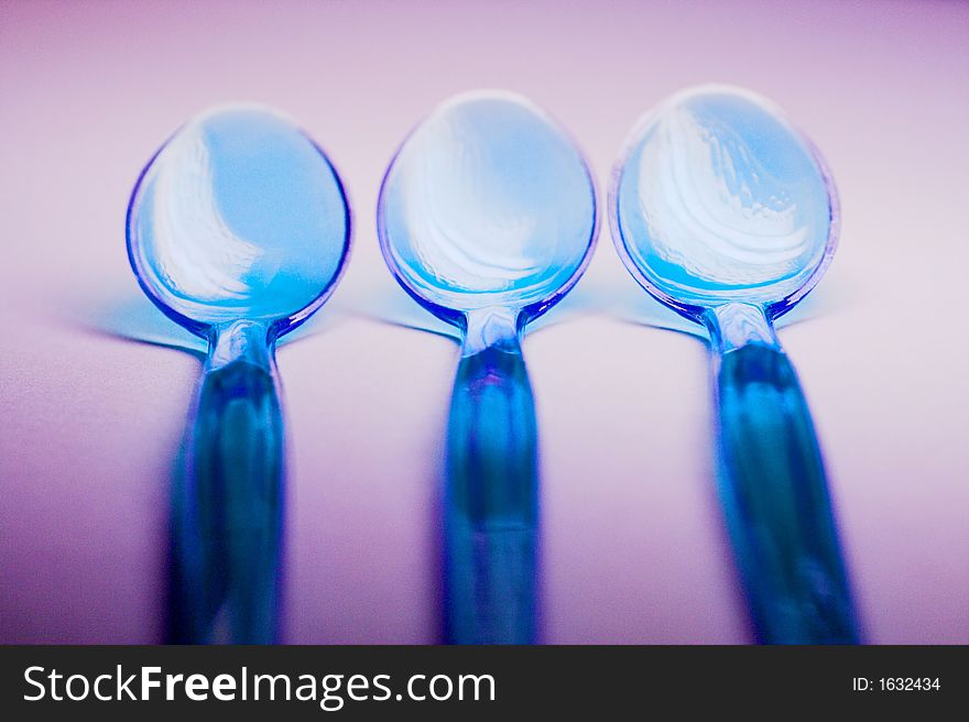 Three transparent blue plastic spoons for eating boiled eggs, neatly put in a row. Three transparent blue plastic spoons for eating boiled eggs, neatly put in a row
