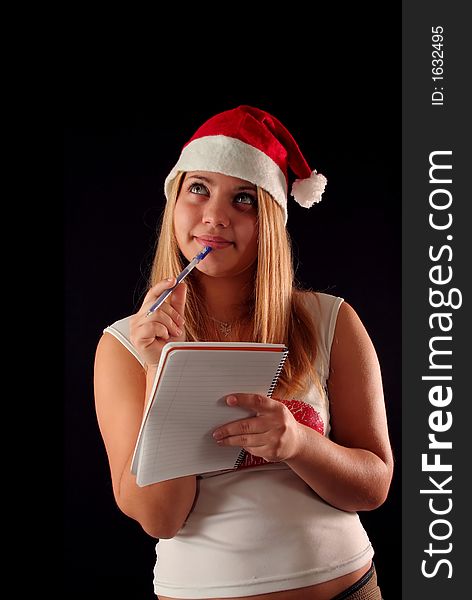 Christmas blonde girl with pencil and bloc notes thinking and writing. Christmas blonde girl with pencil and bloc notes thinking and writing