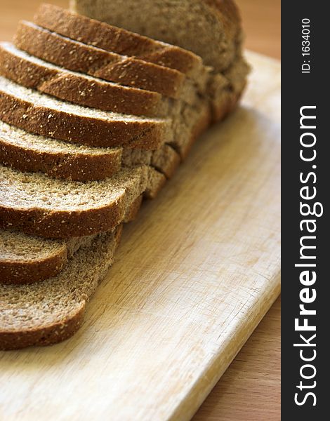 Sliced wholemeal bread arranged on a chopping board - shallow depth of field. Sliced wholemeal bread arranged on a chopping board - shallow depth of field