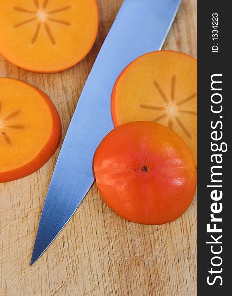 Sliced Persimmon fruits & knife on a chopping block