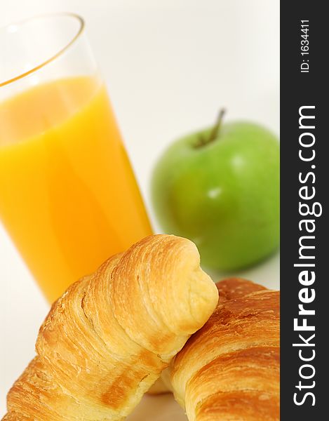 Fresh-baked croissant, orange juice and green apple.  Shallow DOF. Focus on croissant. Fresh-baked croissant, orange juice and green apple.  Shallow DOF. Focus on croissant.