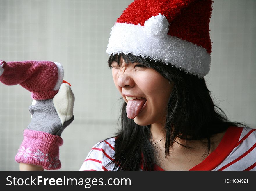 Asian girl sticks tongue out at a christmas puppet. Asian girl sticks tongue out at a christmas puppet