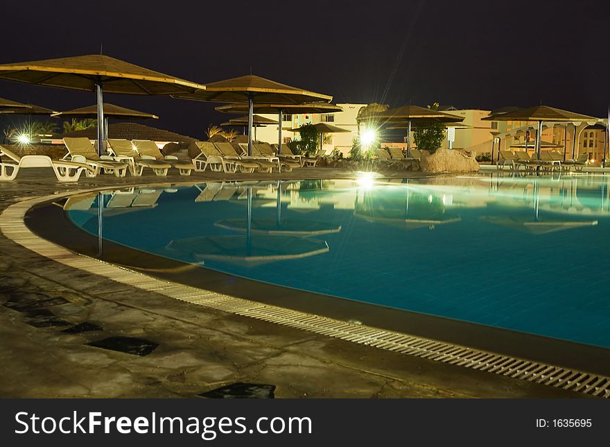 Night picture of rest. swimming-pool, parasols and sunbeds.