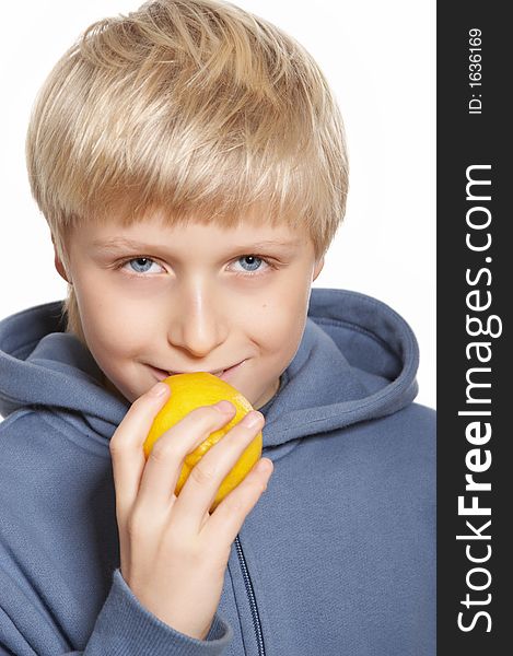 An eleven-year boy eats a lemon and smiles. On white background. An eleven-year boy eats a lemon and smiles. On white background.