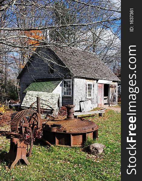 Traditional Blacksmith's cottage with old rusty equipment on the front lawn - rural scenic. Traditional Blacksmith's cottage with old rusty equipment on the front lawn - rural scenic